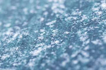 Obraz premium Macro shot of delicate snowflakes sparsely scattered on a frosted blue glass surface
