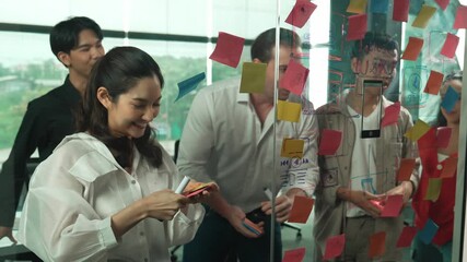 Happy professional business team brainstorming marketing idea by using colorful sticky notes to share creative idea at glass wall. Group of diverse business team discuss about strategy. Manipulator. - Powered by Adobe