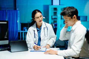 Asian female doctor consulting patient, taking medical history and explaining treatment in modern clinic