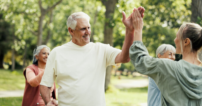 Personal trainer, high five and old people in park with fitness, class and nature for support or help. Retirement, hobby and instructor with elderly group, celebration or workout for wellness advice