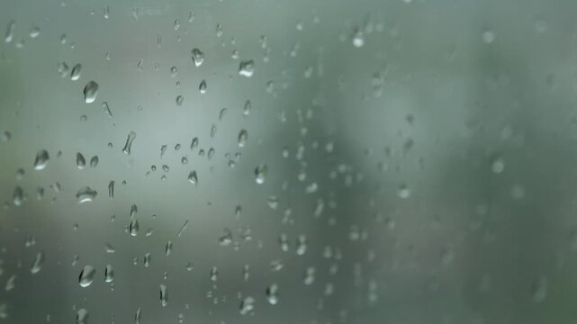 rain drops during raining in rainy day outside window glass with blurred background with water droplet flow down the surface