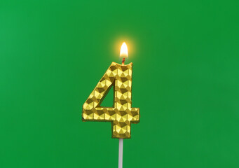 Burning gold birthday candle on green background, number 4