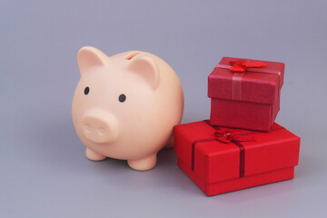 Piggy bank with red gift boxes on grey background. Good price for gifts concept.	