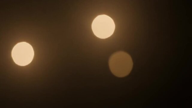 The effect of soft bokeh light wash where blurred light points gently twinkle and dissolve over a dark frame.