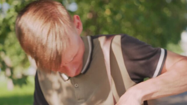 Young Man Startled Reacting To Unseen Noise On TreeLined Street, Sharp Facial Expression, Quick Head Turn, Hands Reach For Bag Strap, Tense Jaw, Candid Emotional Moment In Daylight