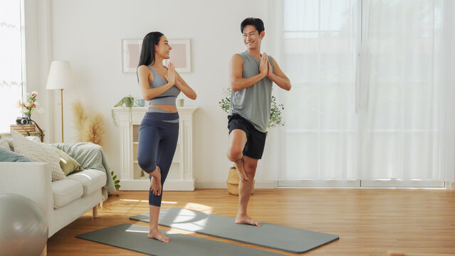 Asian man and woman train balance and stability with yoga exercise, supporting healthy lifestyle at home