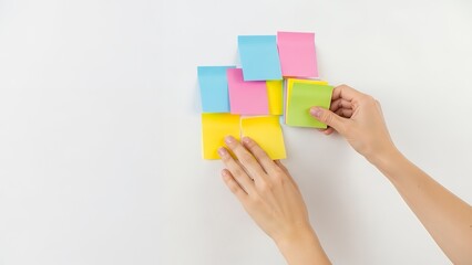 Clean minimal hands arranging few sticky notes on white wall, strategy planning