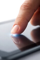 A macro shot of a finger pressing down on a sleek tablet screen with a bright glowing light at the point of contact, representing precision touch technology and human-digital interaction.