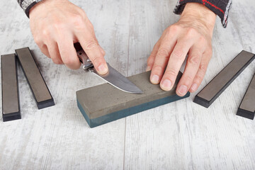Professional sharpening small hunting knife on white table.