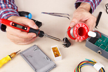 Repair electrical board of device with soldering iron at service workplace.