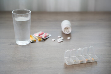 Pill organizer with daily on a table with a glass of water, blister packs, copy space for medication schedule, healthcare, and adherence flatlay, dosage, routine
