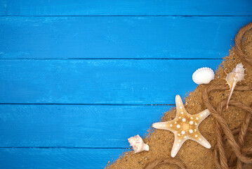 Seashells with starfish and sand on blue wooden. Sea summer vacation background with space for the text. Top view
