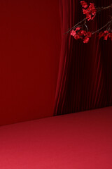 Elegant red monochrome scene with pleated curtain and blossom branch for product presentation.