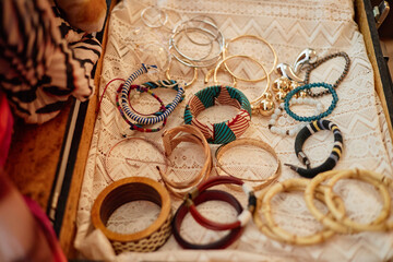 Assorted second hand bracelets and bangles arranged on lace fabric, including wooden, metal, beaded, and fabric wrapped styles, showcasing variety of used jewelry accessories