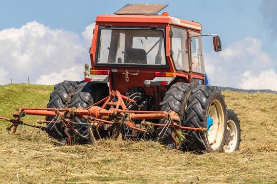 Red tractor with attached hay tedder