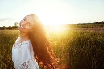Fototapeta premium Portrait, woman and happy for travel in nature for summer adventure, fresh air and holiday trip. Lens flare, female person and space for weekend break, calm morning or vacation getaway in countryside