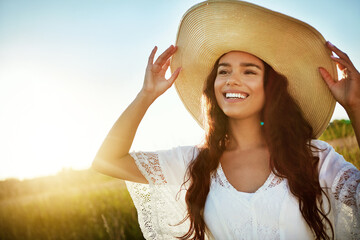 Fototapeta premium Thinking, woman and smile for travel in nature with reflection, fresh air and straw hat on holiday. Space, female person and vacation with vision in field, outdoor view and sightseeing in countryside