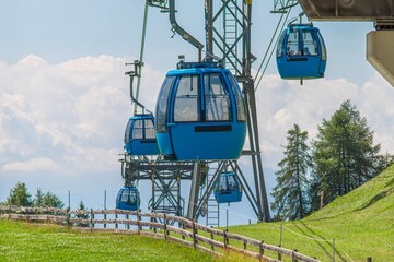 Blue gondola cable cars ascending above green alpine meadows