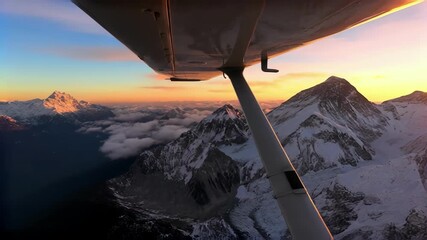 Breathtaking aerial view of snowy mountains at sunset from airplane window - Powered by Adobe
