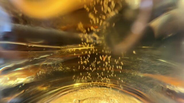 Bottom view through a beer mug shows gentle carbonation as gas bubbles rise upward, creating a relaxing close-up beverage texture.