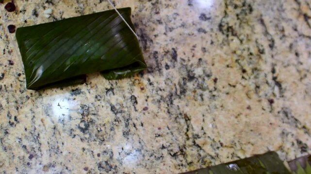Top-down view of woman hands tying traditional Venezuelan hallacas wrapped in plantain leaves, Latin American cuisine, a Christmas culinary tradition.