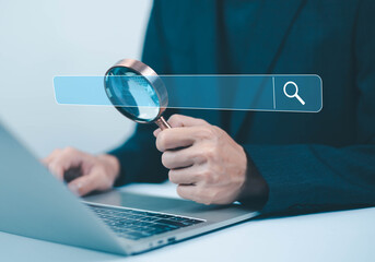 Business data search and analysis concept with businessman holding magnifying glass over laptop, digital search bar interface, online research, SEO strategy, information review and data investigation.