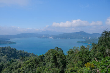 Fototapeta premium Scenic landscape views of Sun Moon Lake in Nantou, Taiwan, featuring calm turquoise water, forested hills, and clear blue skies. These wide-angle photos highlight natural reflections, lush greenery, a