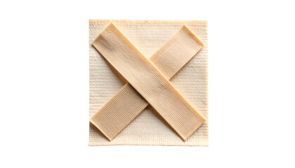 Beige bandages form an X across a textured, square-shaped cream-colored cloth against black