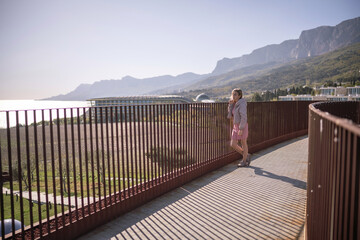 Fototapeta premium Woman standing on modern balcony railing overlooking sea and majestic mountains travel landscape