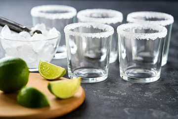 Ingredients and props for making Margarita cocktail with lime and ice on a black  background.