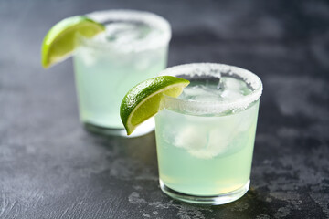Two glasses of tasty Margarita cocktail on a black table, selective focus.