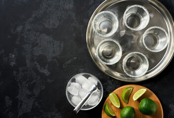 Ingredients and props for making Margarita cocktail with lime and ice on a black  background. Top view with copy space.