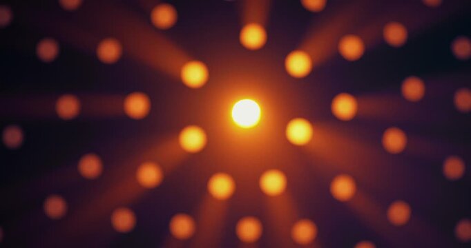 Warm yellow light shines through round holes in a black background. The intensity of the glow increases and decreases