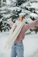Young woman enjoying falling snow in winter park