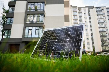 Photovoltaic solar panel in front of modern apartment building with balconies, suggesting residential or mixed-use. Concept of integration of sustainable renewable energy sources into architecture.