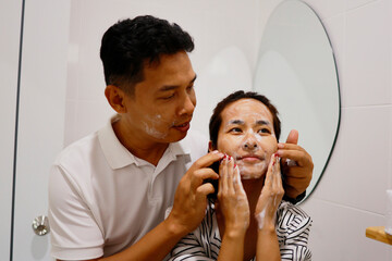 Woman and man washes her face in the morning with facial foam.