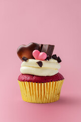 Red velvet cupcake with cream cheese frosting and heart chocolate decorated for valentines day on pink background