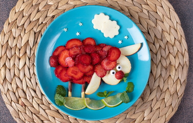 Sheep animal with strawberry, apple and lime laid out on blue plate - fun idea children breakfast