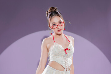 Elegant Asian model in white lace corset top and ruffled mini skirt with red ribbon accents, posing confidently in sheer red stockings and nude high heels, glamorous studio portrait soft blue scene