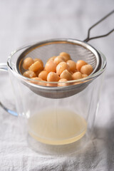 A close-up image of canned chickpeas draining on a sieve against a gray fabric background