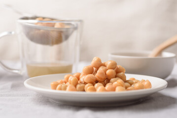 A close-up image of canned chickpeas placed on a white ceramic plate, ready for cooking