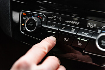 Fototapeta premium Hand pressing the button for interior heating and heated seats in the car in winter.