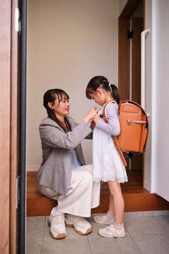 Mother helping daughter get ready for school at home entrance