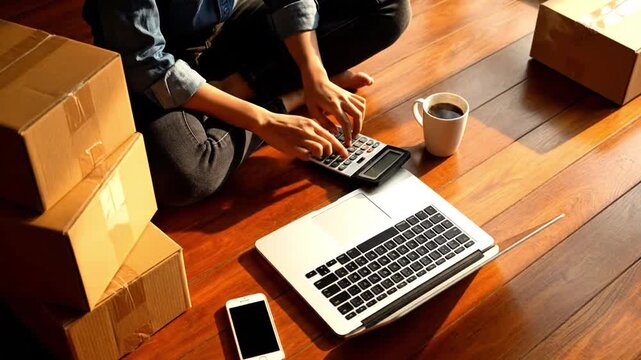 Female Small Business Owner Calculating Costs on Floor with Laptop, Home Office