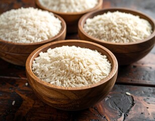 Four wooden bowls filled with grains of rice on a dark wood surface under soft lighting, showing texture and detail