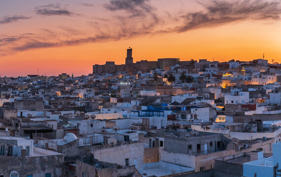 Sunset view over the historic medina of Sousse, Tunisia, with dense urban rooftops and warm evening light, evoking culture, tradition, everyday city life, and North African atmosphere