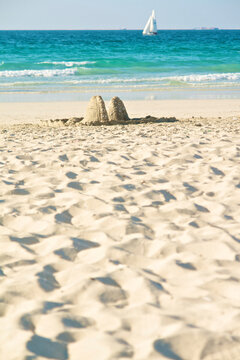 Sandcastle on Jumeirah Beach Dubai with sailboat on turquoise sea