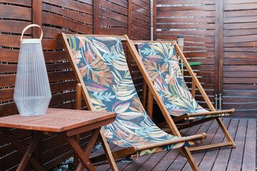 Deck chairs with tropical pattern on wooden terrace for relaxation