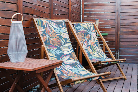 Deck chairs with tropical pattern on wooden terrace for relaxation