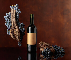 Red wine with a weathered snag and blue grapes on a brown background.